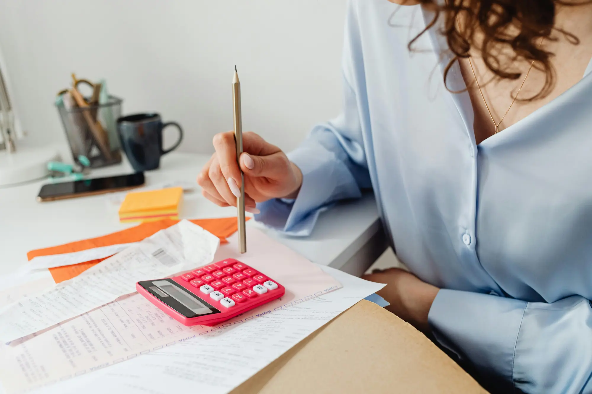 A woman diligently calculates her taxes with a calculator, showcasing her commitment to financial responsibility.